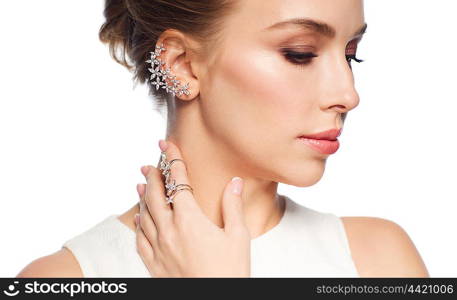 luxury, wedding and people concept - smiling woman in white dress with diamond jewelry over white background (focus on earring ang ring on finger)