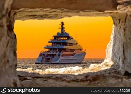Luxury yacht on golden sunset through stone window view