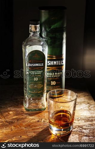 LVIV, UKRAINE - DECEMBER 04: Bottle of Bushmills whisky and glass on wooden shelf on December 04, 2017 in Lviv