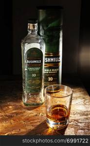LVIV, UKRAINE - DECEMBER 04: Bottle of Bushmills whisky and glass on wooden shelf on December 04, 2017 in Lviv