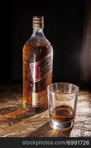 LVIV, UKRAINE - DECEMBER 04: Bottle of Johnnie Walker whisky and glass on wooden shelf on December 04, 2017 in Lviv