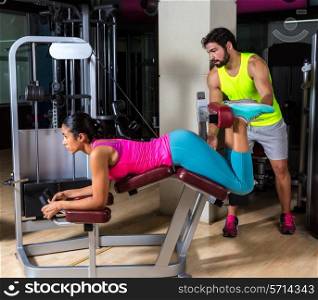 Lying hamstring curl machine girl with personal trainer man