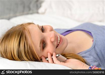Lying joyful teenager girl talking on her phone in bed