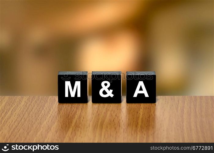 M&amp;A or merger and acquisition on black block with blurred background