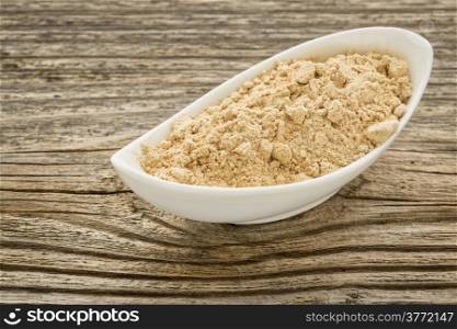 maca root powder in a small ceramic bowl against grained wood