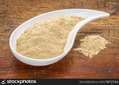 maca root powder in a teardrop shaped bowl against grunge wood