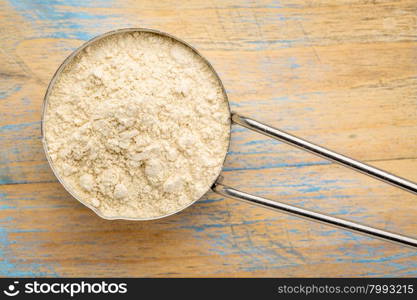 maca root powder on a metal measuring scoop against painted wood