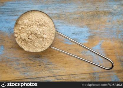 maca root powder on a metal measuring scoop against painted wood