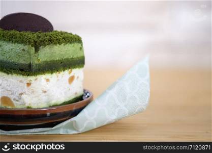 Macadamia cake with greentea and white cream on wooden table, close up, space to write, Select a focus, blurred