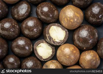 macadamia nuts in shell and dipped in dark chocolate on a black plate