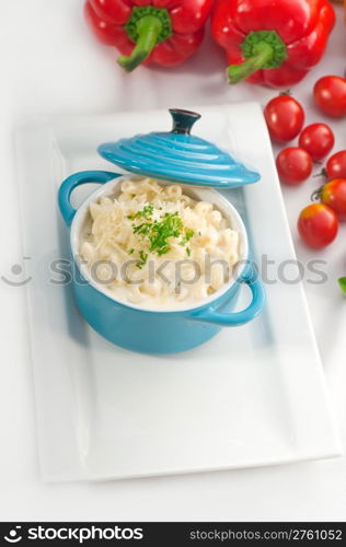 macaroni and cheese,kids favourite dish , on a blue little childish clay pot with vegetables on background,MORE DELICIOUS FOOD ON PORTFOLIO