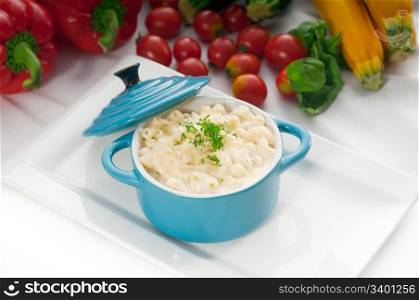 macaroni and cheese,kids favourite dish , on a blue little childish clay pot with vegetables on background,MORE DELICIOUS FOOD ON PORTFOLIO