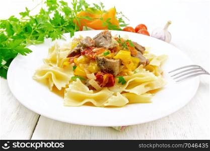 Macaroni Farfalle with turkey meat, tomato, yellow sweet pepper with sauce in a plate on the background of a light wooden board