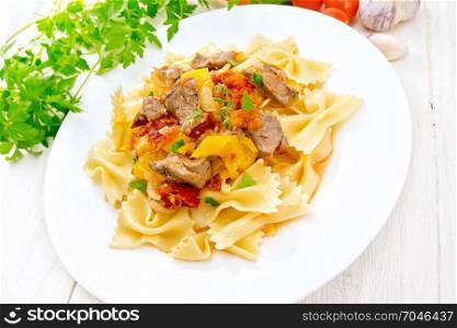 Macaroni Farfalle with turkey meat, tomato, yellow sweet pepper with sauce in a plate, garlic, parsley on a light wooden board background
