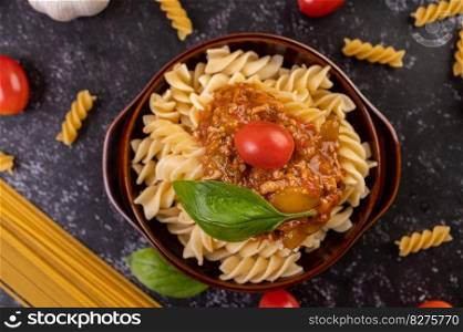 Macaroni sauteed with tomatoes and basil on a gray plate.