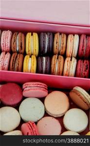 Macarons in different colors and flavors in a pink box