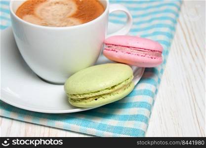 Macaroons and one white cup of coffee . Macaroons and cup of coffee 