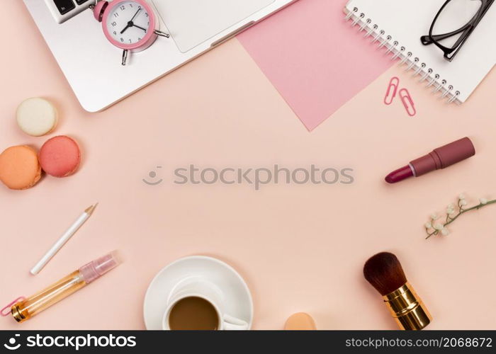 macaroons coffee cup makeup brushes alarm clock laptop peach colored background