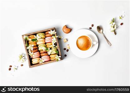 Macaroons in wooden box with spring flowers and cup of coffee flat lay. Macaroons in wooden box with spring flowers and cup of coffee