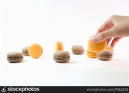 Macaroons on white background and hand holding one, colorful macaroons, selective focus.. Macaroons on white background and hand holding one, colorful macaroons, selective focus