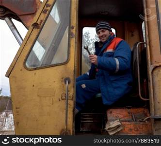 Machinist excavator with spanner in hand in the cab