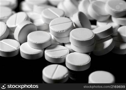 Macro Close up of white painkiller tablet on a reflective black background