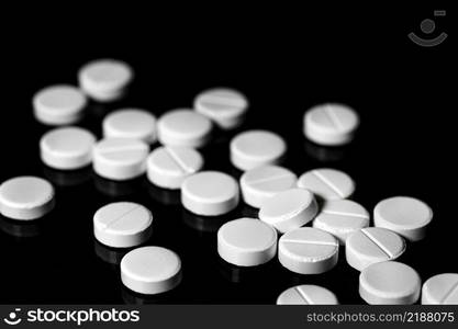 Macro Close up of white painkiller tablet on a reflective black background