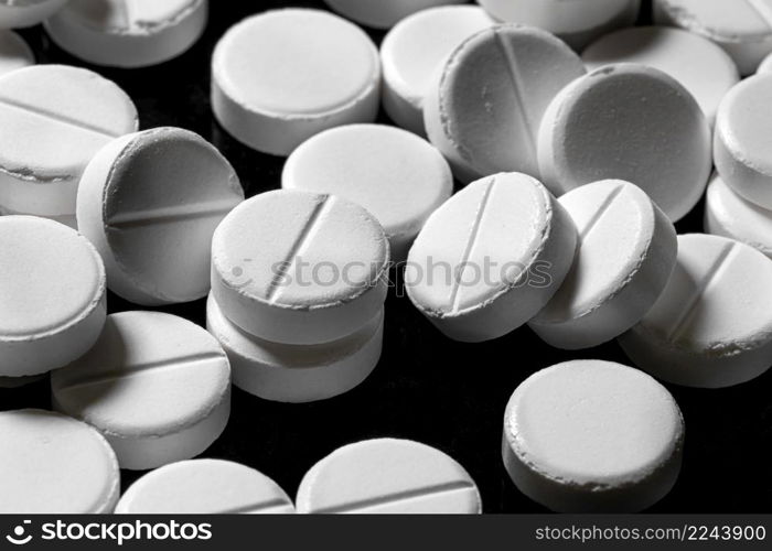 Macro Close up of white painkiller tablet on a reflective black background