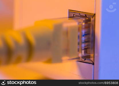 Macro close up of WiFi extender in electrical socket on the wall with ethernet cable plugged in. The device is in access point mode that help to extend wireless network in home or office.