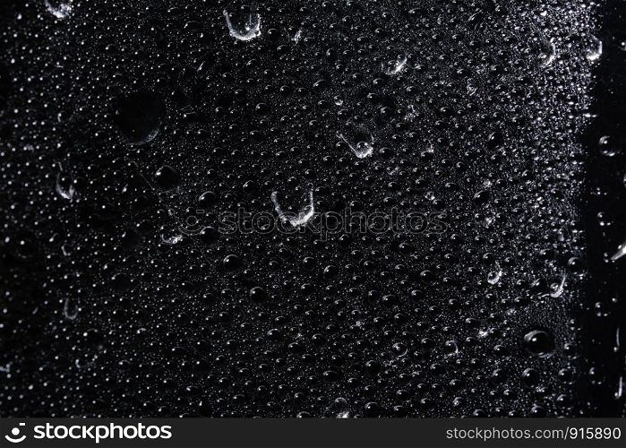 Macro droplet on transparent plastic sheet, black background
