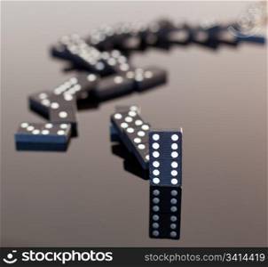 Macro image of dominos on a black reflactive surface and collapsed in pile