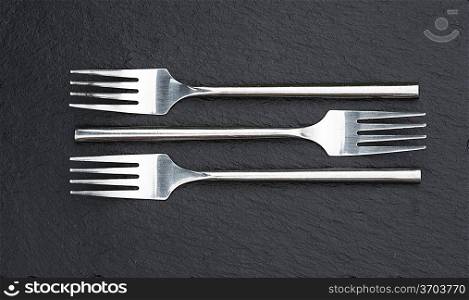 Macro image of modern cutlery forks on rustic slate background
