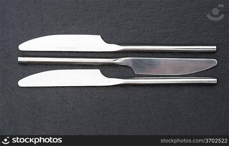 Macro image of modern cutlery knives on rustic slate background