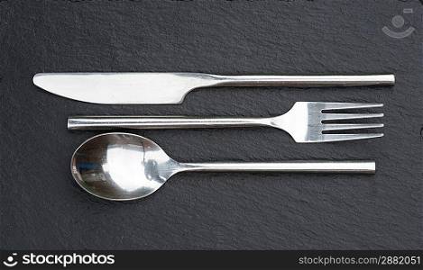 Macro image of modern cutlery set on rustic slate background