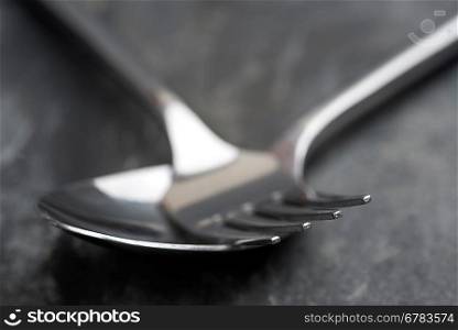Macro image of modern fork and spoon on rustic slate background