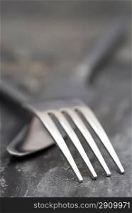 Macro image of modern knife and fork on rustic slate background