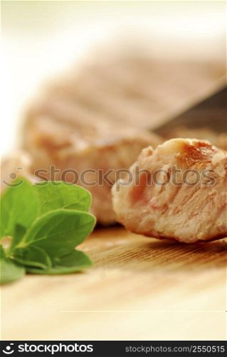 Macro of a grilled steak being cut on a cutting board