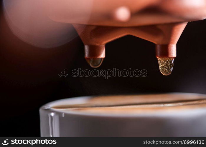 Macro photo of a coffee machine with drops of drink and a cup of freshly made coffee. Espresso Brewing. Macro photo of a cup of hot coffee from the coffee machine. Professional coffee brewing