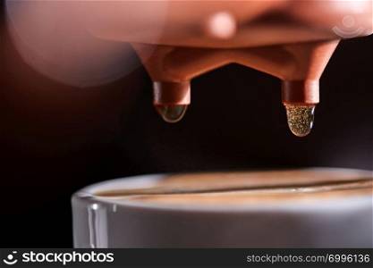 Macro photo of a coffee machine with drops of drink and a cup of freshly made coffee. Espresso Brewing. Macro photo of a cup of hot coffee from the coffee machine. Professional coffee brewing