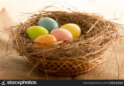 Macro photo of colorful Easter eggs lying in nest on the table