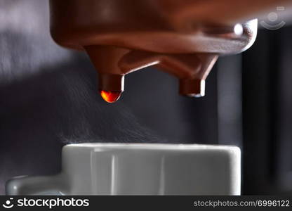 Macro photo of dripping coffee in a coffee machine dripping into a cup. The process of making a drink. Macro photo of making coffee in the coffee machine. Drops of coffee dripping into the cup