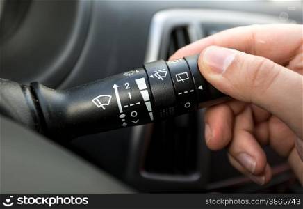 Macro photo of driver adjusting windscreen wipers control toggle