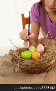 Macro photo of girl holding paintbrush and coloring Easter eggs
