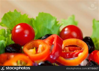 Macro photograph of fresh lettuce, tomato, pepper, black olive, red onion and red cabbage salad