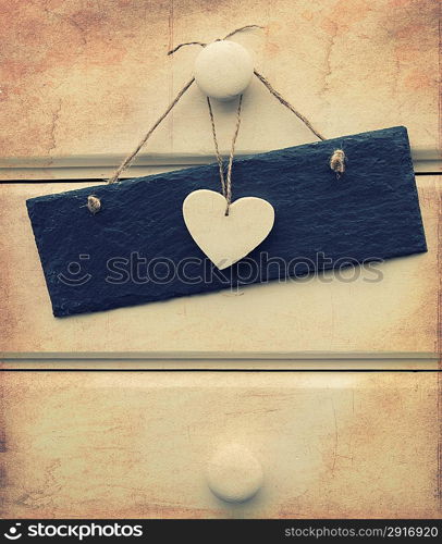 Macro retro cross processed effect image of heart and slate sign on wooden background