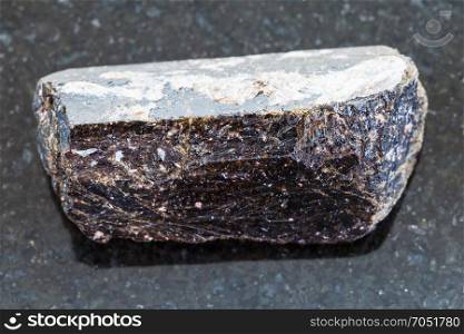 macro shooting of natural mineral rock specimen - crystal of dravite tourmaline gemstone on dark granite background from China