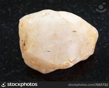 macro shooting of natural mineral rock specimen - pebble of Calcite stone on dark granite background