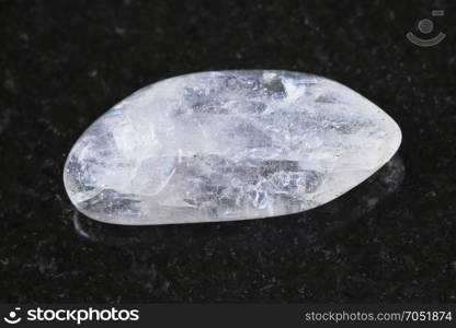 macro shooting of natural mineral rock specimen - pebble of Natrolite gemstone on dark granite background from Lovozero Massif, Kola peninsula, Russia