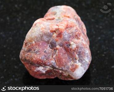 macro shooting of natural mineral rock specimen - pebble of Pegmatite stone on dark granite background