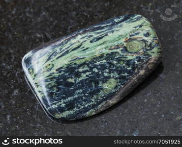 macro shooting of natural mineral rock specimen - polished rhyolite gemstone on dark granite background from Madagascar